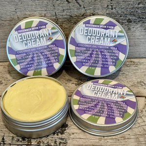 Four tins of deodorant cream with purple labels on a wooden surface