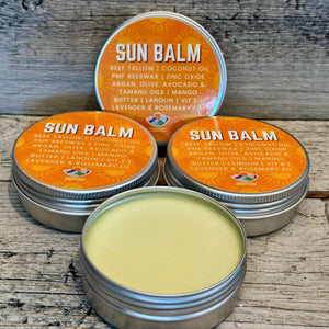 Sun balm tins with visible ingredients on a wooden surface